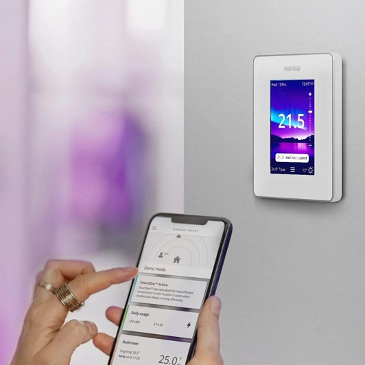 Warmup 7iE WiFi Matter: Termostato Inteligente Universal para Suelo Radiante - vista diagonal blanco en pared y app - Q-Tech® 2026